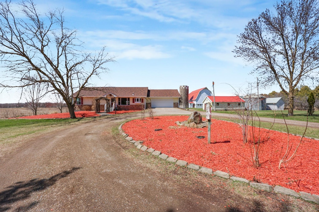 ranch-style home with dirt driveway and a garage