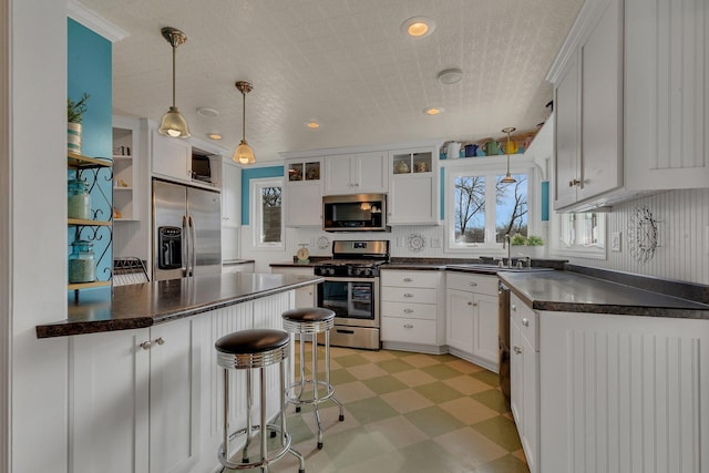 1205 Melvina Rd SW, Alexandria, MN 56308 - kitchen with dark countertops, appliances with stainless steel finishes, a sink, light floors, and white cabinetry