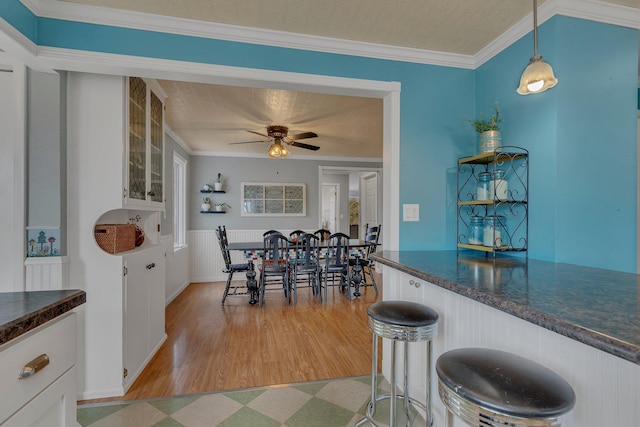 1205 Melvina Rd SW, Alexandria, MN 56308 - dining space with a bar, crown molding, light floors, and ceiling fan