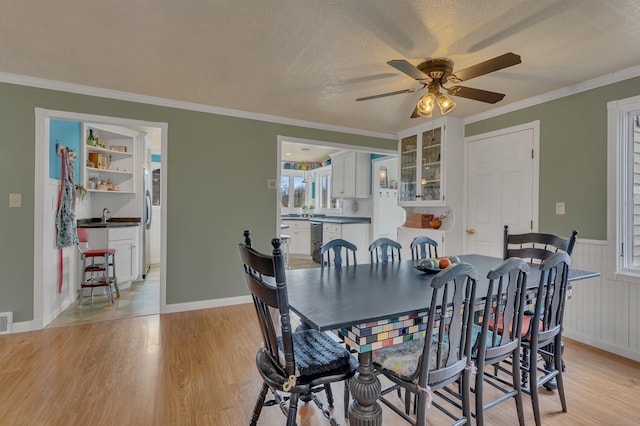 1205 Melvina Rd SW, Alexandria, MN 56308 - dining space with wainscoting, a ceiling fan, ornamental molding, and light wood finished floors