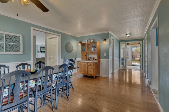 1205 Melvina Rd SW, Alexandria, MN 56308 - dining area with crown molding, ceiling fan, light wood finished floors, and a wainscoted wall