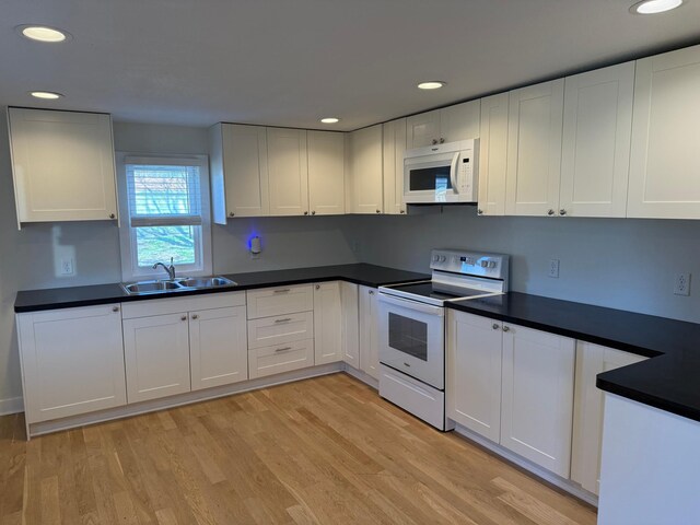 436 Adams St SE, Hutchinson, MN 55350 - kitchen featuring dark countertops, a sink, light wood-style floors, white appliances, and white cabinetry