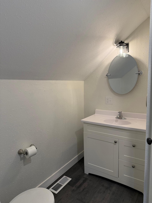 436 Adams St SE, Hutchinson, MN 55350 - half bath with vanity, toilet, wood finished floors, lofted ceiling, and visible vents