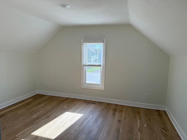 436 Adams St SE, Hutchinson, MN 55350 - bonus room featuring visible vents, baseboards, lofted ceiling, and wood finished floors