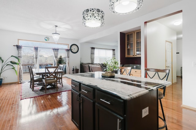 kitchen with light stone countertops, a breakfast bar, a kitchen island, and light wood-style flooring