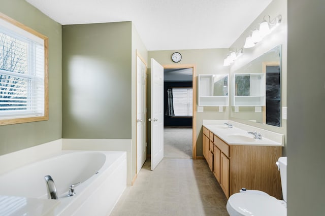 bathroom featuring a bath, toilet, double vanity, and plenty of natural light