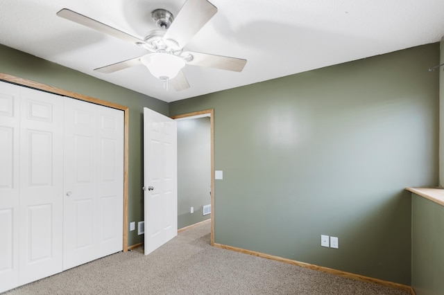 unfurnished bedroom with a closet, a ceiling fan, baseboards, and light carpet
