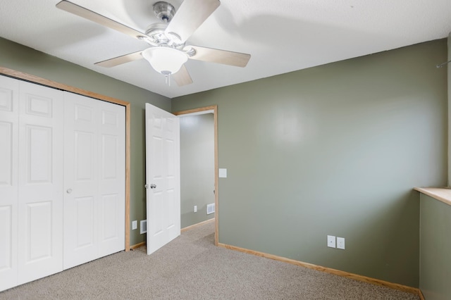 unfurnished bedroom featuring a closet, carpet flooring, baseboards, and ceiling fan