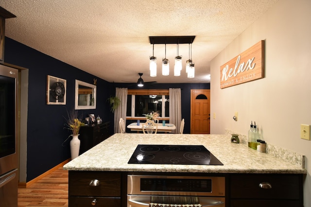 1164 Hawthorn St, Red Wing, MN 55066 - kitchen with stainless steel oven, black electric cooktop, a textured ceiling, light wood finished floors, and light countertops