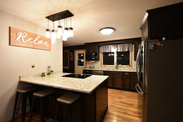 1164 Hawthorn St, Red Wing, MN 55066 - kitchen with stainless steel appliances, a peninsula, a textured ceiling, light wood-style floors, and a sink