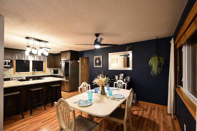 1164 Hawthorn St, Red Wing, MN 55066 - dining room with light wood-type flooring, a ceiling fan, a textured ceiling, and baseboards