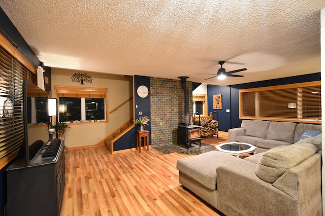 1164 Hawthorn St, Red Wing, MN 55066 - living area featuring a wood stove, stairway, ceiling fan, baseboards, and light wood-style floors
