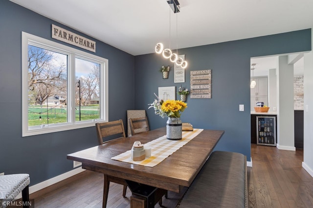 dining space featuring baseboards, wine cooler, a chandelier, and hardwood / wood-style flooring