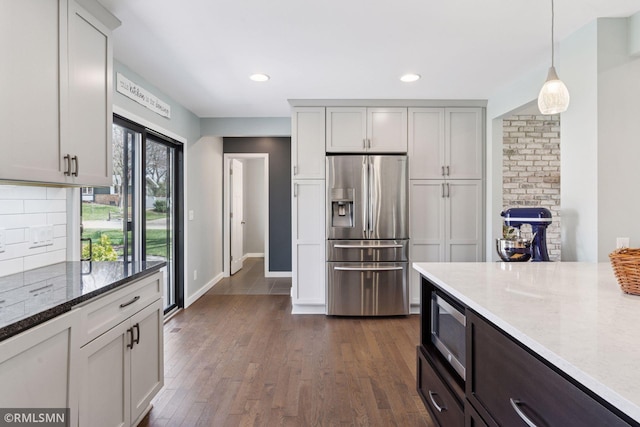 kitchen featuring backsplash, hanging light fixtures, light stone counters, baseboards, and stainless steel appliances