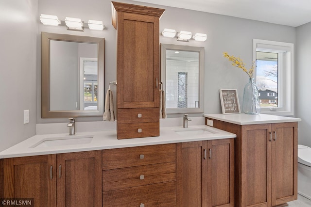 bathroom with double vanity, toilet, and a sink