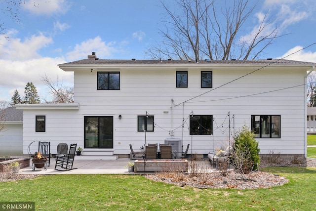 rear view of house featuring central AC unit, a chimney, a patio, a yard, and a fire pit