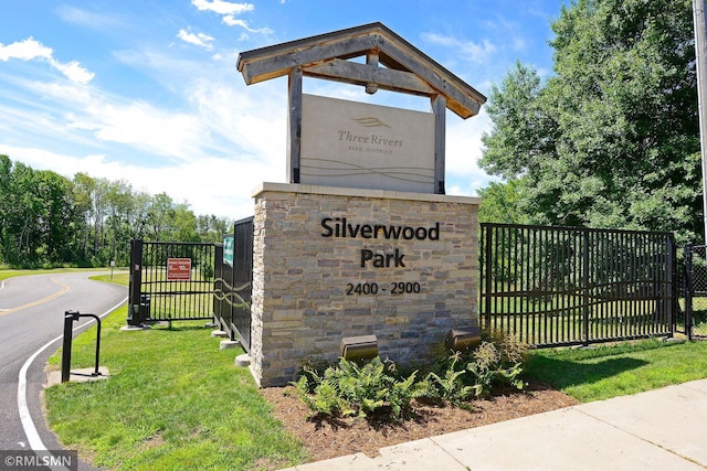 community / neighborhood sign featuring fence and a yard