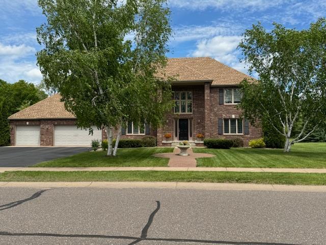 5214 381st Ln, North Branch, MN 55056 - view of front of house featuring brick siding, a front lawn, driveway, and an attached garage