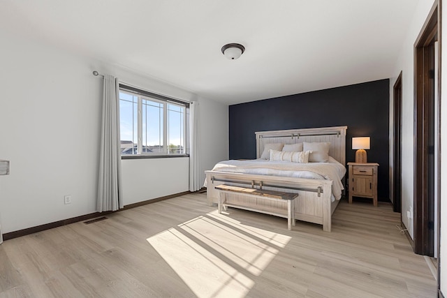 1101 8th Ave SW, Isanti, MN 55040 - bedroom featuring an accent wall, light wood-style flooring, and baseboards