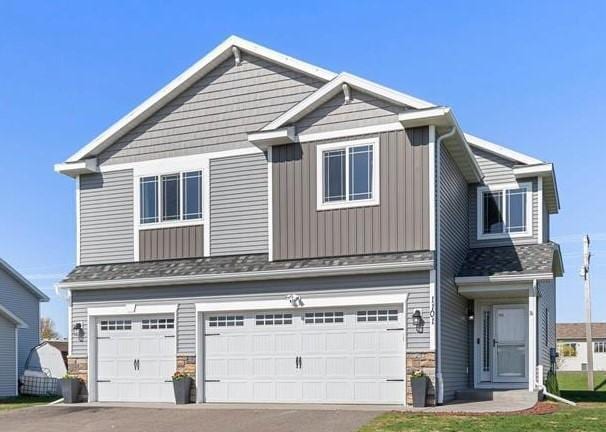 1101 8th Ave SW, Isanti, MN 55040 - craftsman-style home featuring an attached garage, stone siding, driveway, and board and batten siding