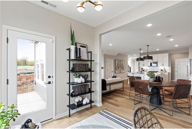 dining space featuring a chandelier, light wood-style floors, recessed lighting, and baseboards