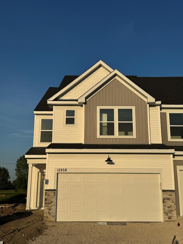 view of front of house featuring an attached garage, stone siding, and driveway