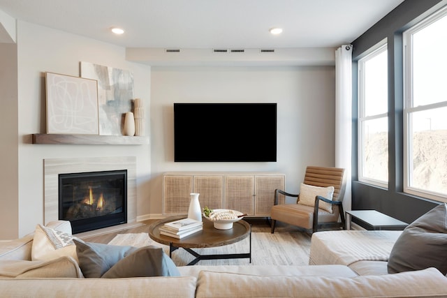 living area featuring wood finished floors, recessed lighting, and a glass covered fireplace