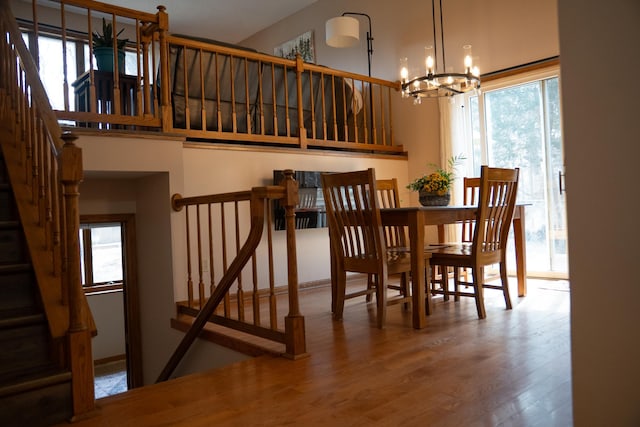 dining area featuring a wealth of natural light, a chandelier, wood finished floors, and stairway