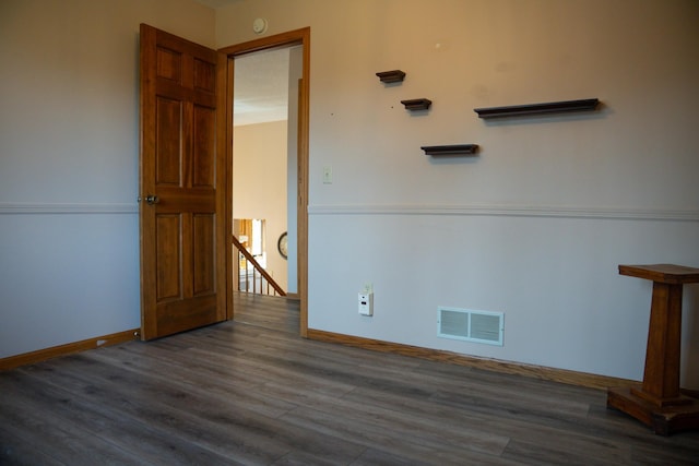 unfurnished room with wood finished floors, visible vents, and baseboards