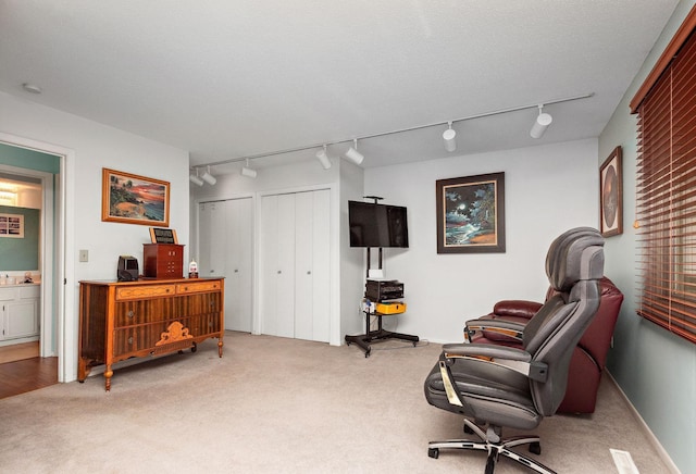 sitting room with baseboards, rail lighting, and light carpet