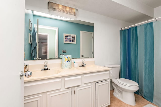 full bathroom with double vanity, a sink, tile patterned flooring, and toilet