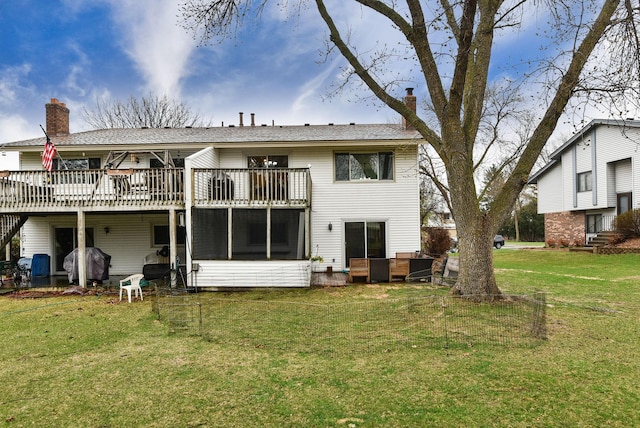 back of house featuring a yard, a chimney, a sunroom, and a wooden deck