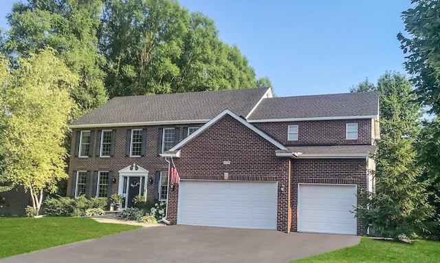 colonial home featuring brick siding, aphalt driveway, a shingled roof, a front yard, and an attached garage