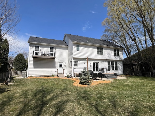 rear view of property with fence, a patio, entry steps, a balcony, and a lawn