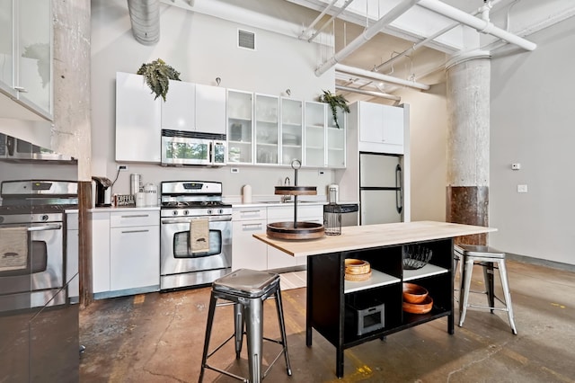 700 Washington Ave N Unit 210, Minneapolis, MN 55401 - kitchen with appliances with stainless steel finishes, ornate columns, white cabinets, a towering ceiling, and concrete flooring