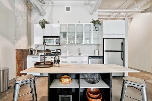 700 Washington Ave N Unit 210, Minneapolis, MN 55401 - kitchen with stainless steel appliances, white cabinets, a breakfast bar area, and concrete flooring