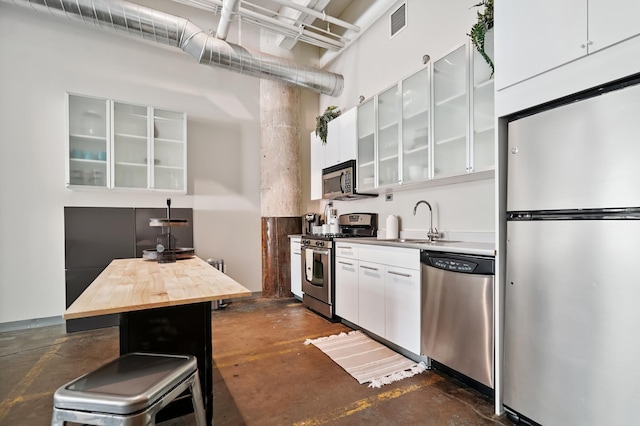 700 Washington Ave N Unit 210, Minneapolis, MN 55401 - kitchen featuring appliances with stainless steel finishes, concrete flooring, white cabinets, wood counters, and glass insert cabinets