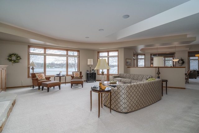 living area with a water view, baseboards, and carpet