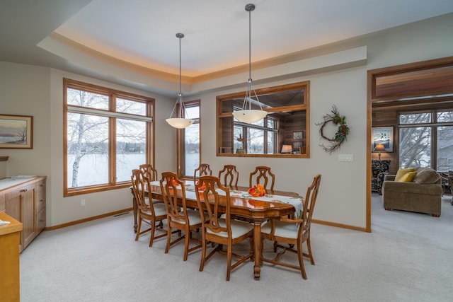 dining room featuring light colored carpet, baseboards, and a tray ceiling