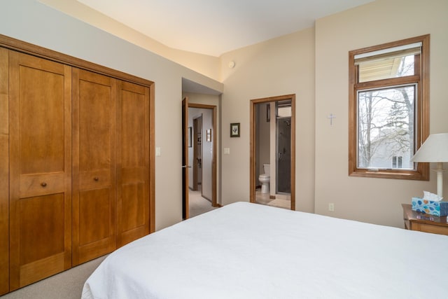 bedroom featuring ensuite bathroom, lofted ceiling, and light carpet