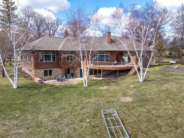 rear view of property featuring a lawn, a chimney, a patio area, and a wooden deck