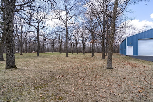 view of yard featuring an outdoor structure, a garage, and aphalt driveway
