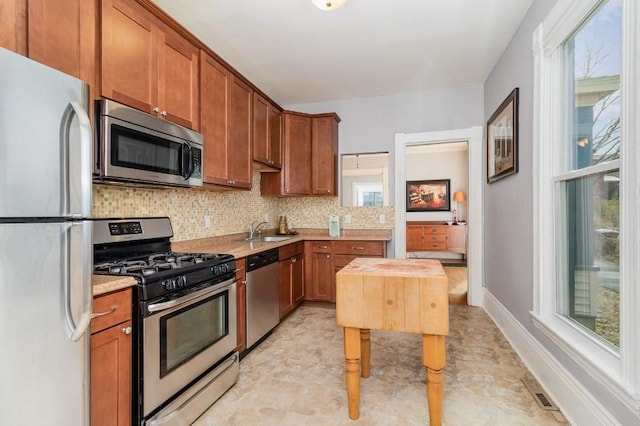 2530 Pleasant Ave, Minneapolis, MN 55404 - kitchen featuring light countertops, brown cabinetry, appliances with stainless steel finishes, and decorative backsplash