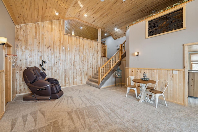 living area with stairway, wooden ceiling, wooden walls, and carpet