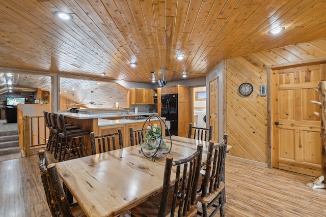 dining area featuring wood walls, light wood-style flooring, and washer / clothes dryer