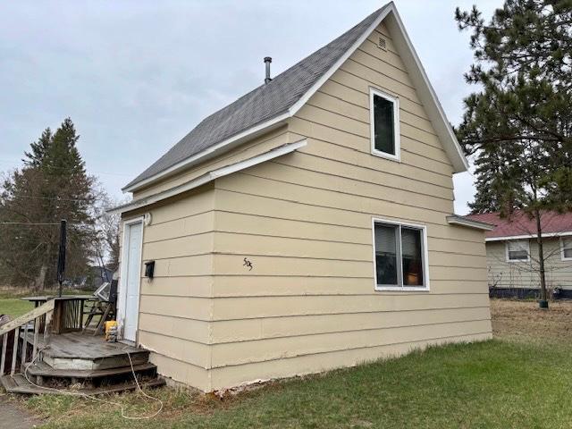 view of side of property with a shingled roof and a wooden deck