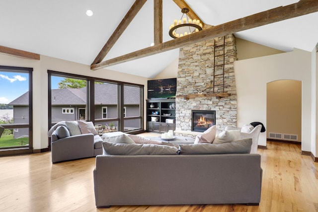 3420 Fairview Ave N, Arden Hills, MN 55112 - living area featuring high vaulted ceiling, plenty of natural light, a stone fireplace, beamed ceiling, and light wood-type flooring