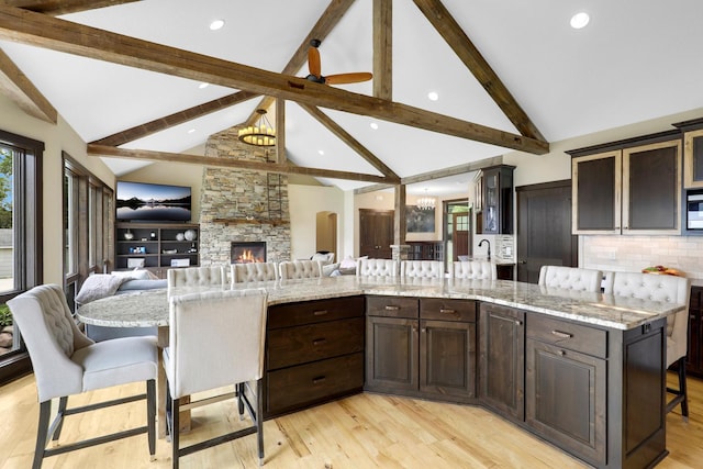 3420 Fairview Ave N, Arden Hills, MN 55112 - kitchen featuring open floor plan, beamed ceiling, a breakfast bar, dark brown cabinets, and light wood-style flooring