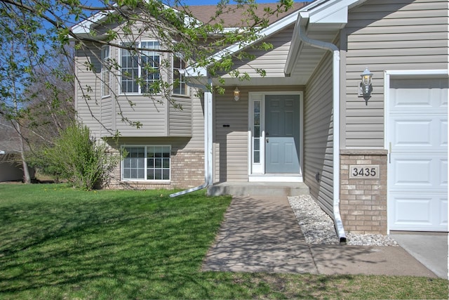 doorway to property with a lawn, brick siding, and an attached garage