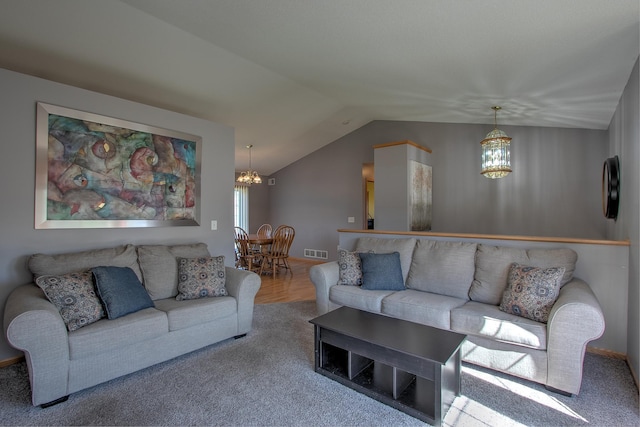 living area featuring carpet flooring, vaulted ceiling, a chandelier, and visible vents